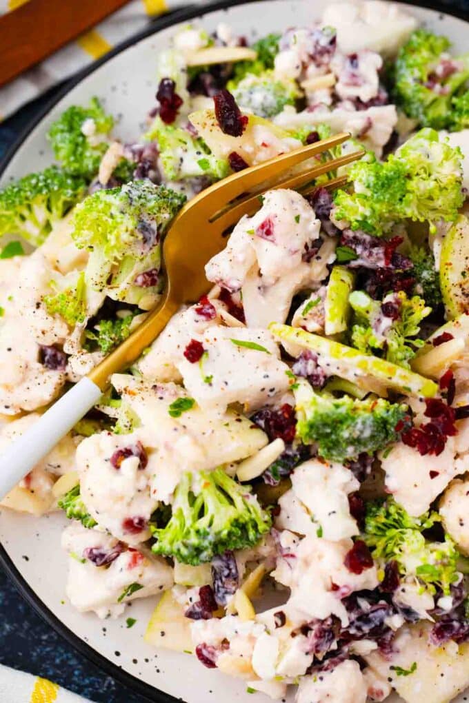 A plate of broccoli cauliflower salad with a fork resting in it