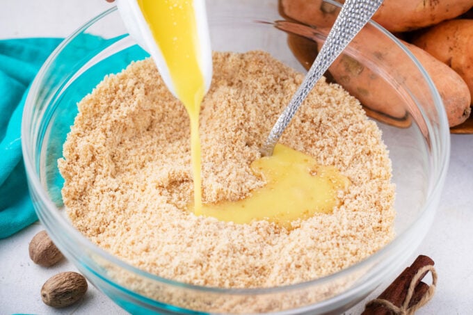 Adding melted butter to graham cracker crumbs.