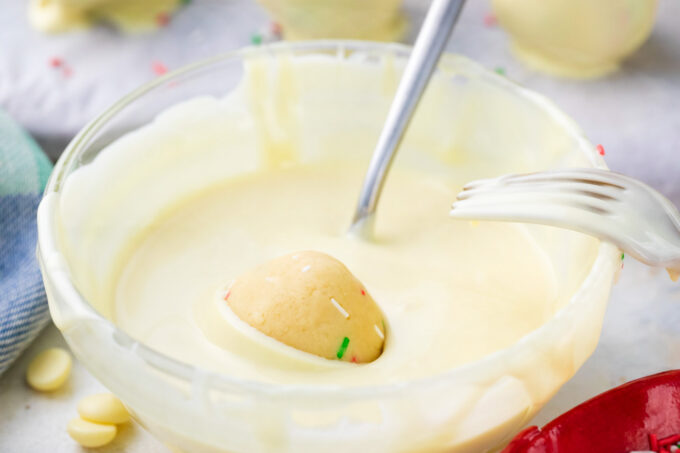 Dipping sugar cookie truffle into white chocolate.