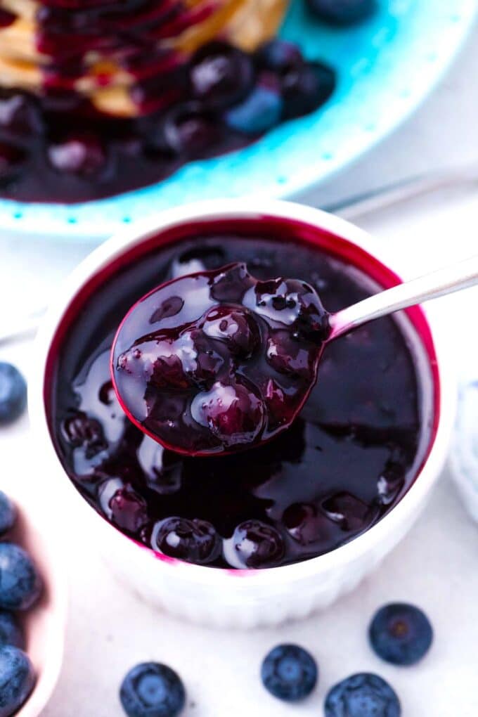 a spoonful of homemade blueberry sauce over a ramekin with the sauce