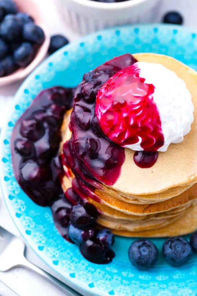 homemade blueberry sauce dripping of a stack of pancakes