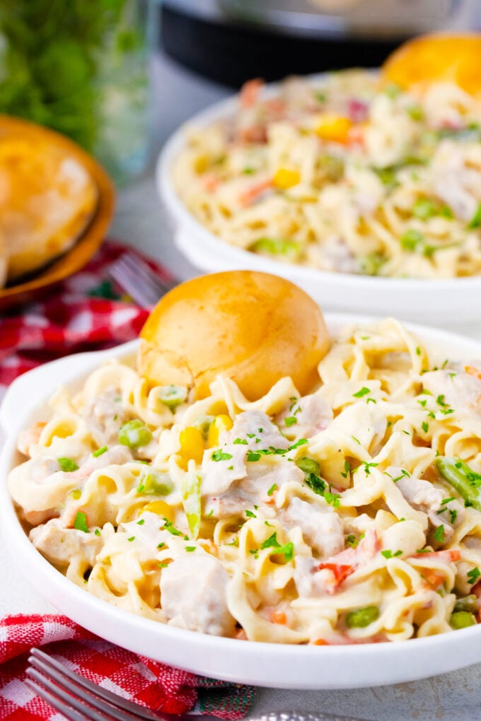 Cheesy instant pot chicken pot pie pasta served with a buttery biscuit.