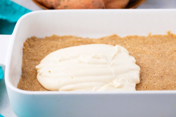 Adding a cheesecake payer on top of graham cracker crust.