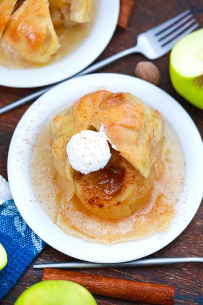 overhead shot of homemade apple dumplings on a plate topped with whipped cream