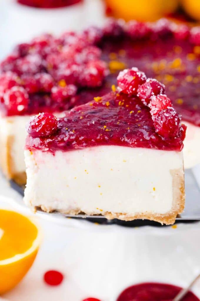 a slice of sliced cranberry cheesecake topped with cranberry sauce and sugared cranberries