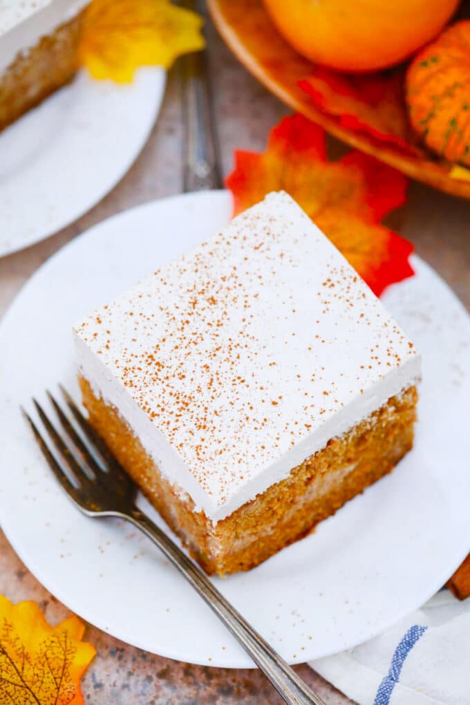 A slice of tres leches pumpkin cake with cinnamon whipped cream.