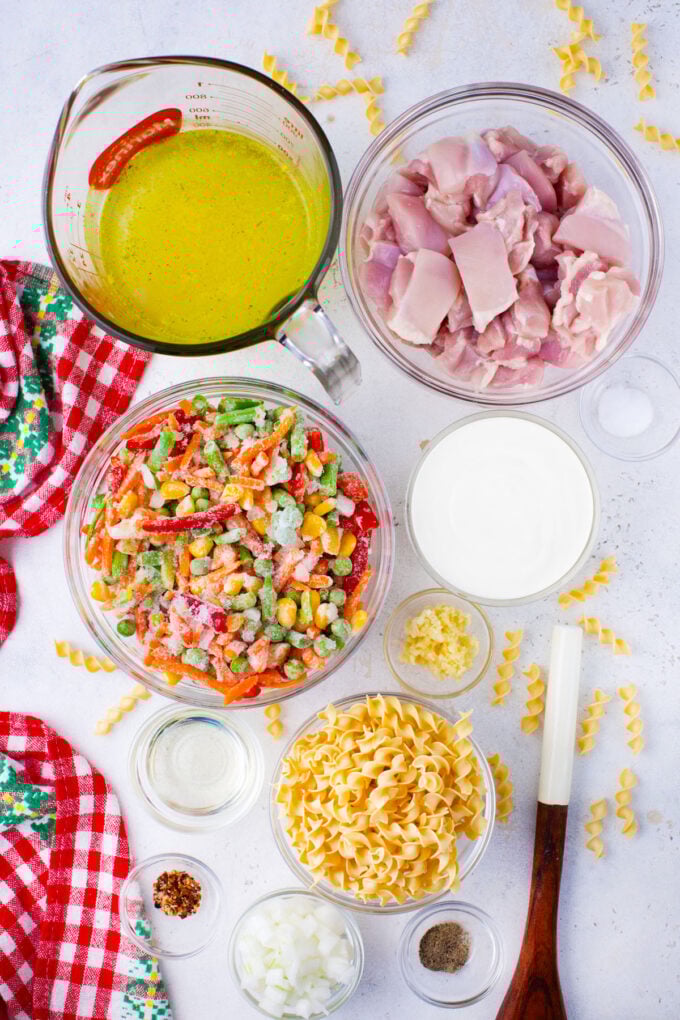 Overhead shot of instant pot chicken pot pie pasta ingredients in bowls on a table.