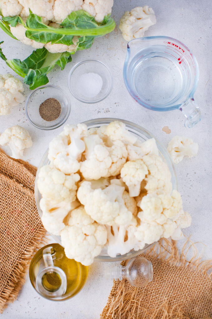 Overhead shot of Instant Pot mashed cauliflower ingredients in a white surface.