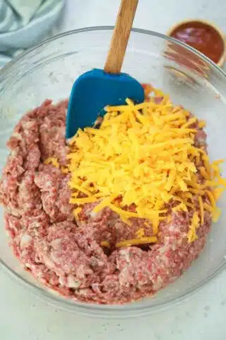adding cheddar cheese to meatloaf mixture