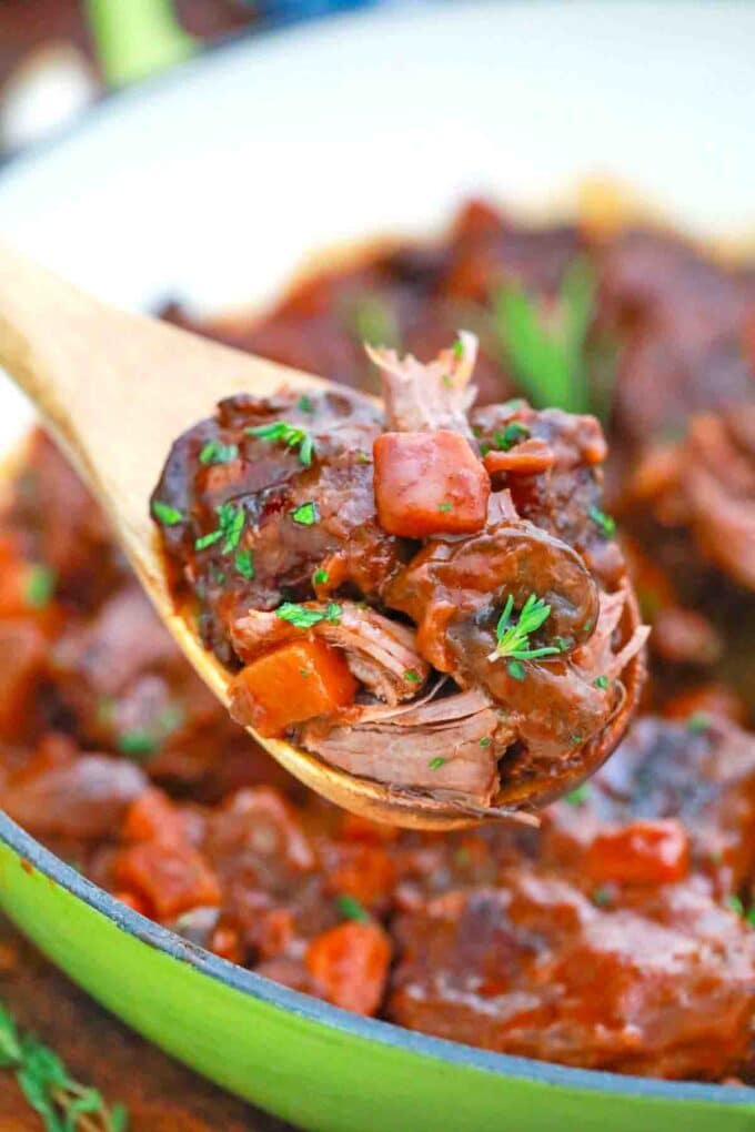 a wooden spoon holding beef and mushrooms