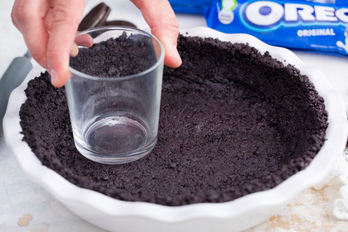 Pressing Oreo crust into a pie dish.