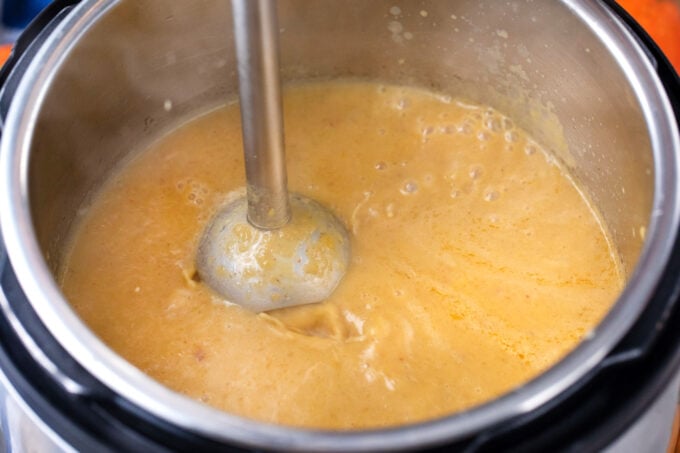 Blending instant pot pumpkin soup with an immersion blender.