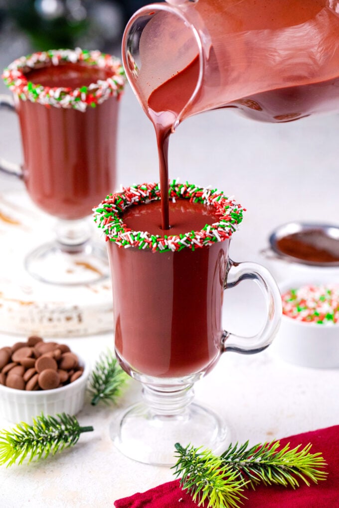 Pouring red velvet hot chocolate in a cup.