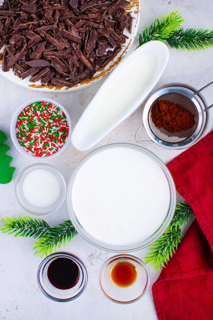 Overhead shot of red velvet hot chocolate ingredients in bowls on a white surface.