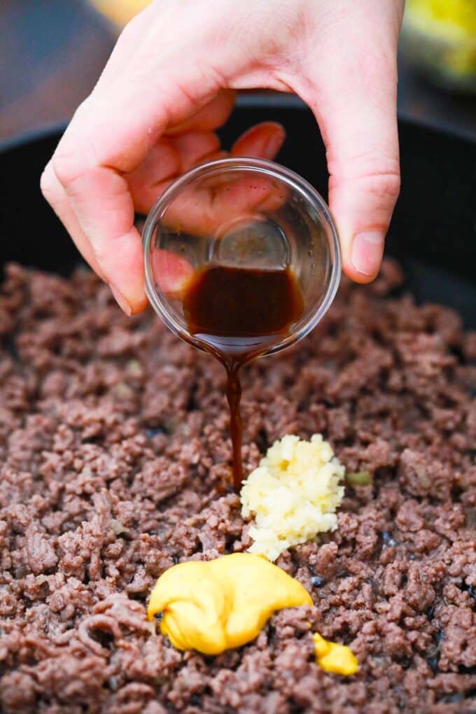 Seasoning ground beef in a pan.