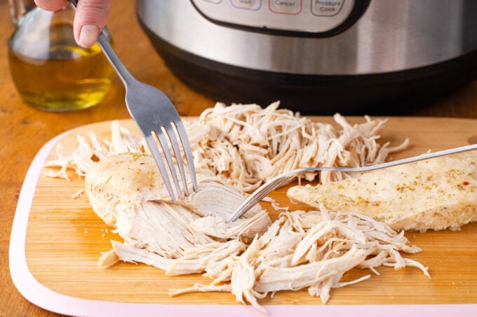 Shredding chicken breasts with two forks.