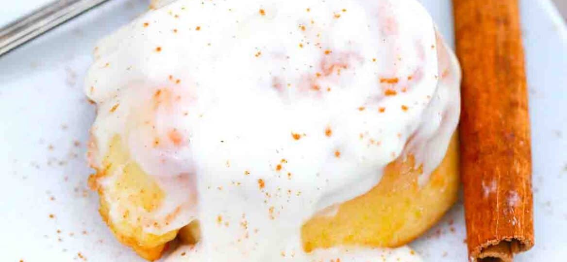 crockpot cinnamon roll on a plate topped with icing