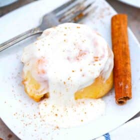 crockpot cinnamon roll on a plate topped with icing