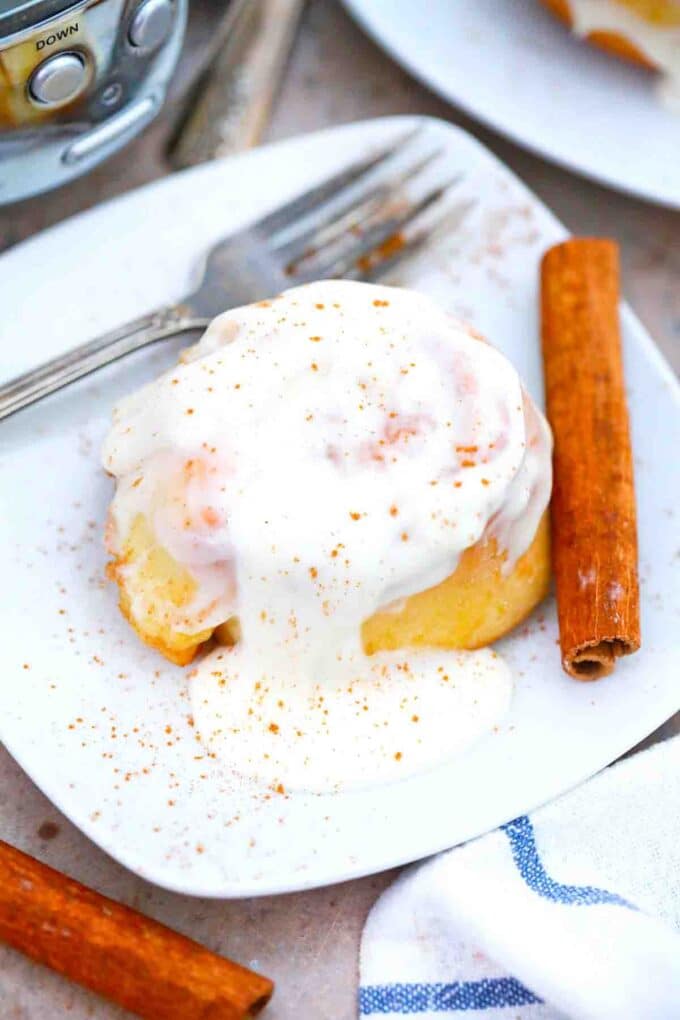 crockpot cinnamon roll on a plate topped with icing