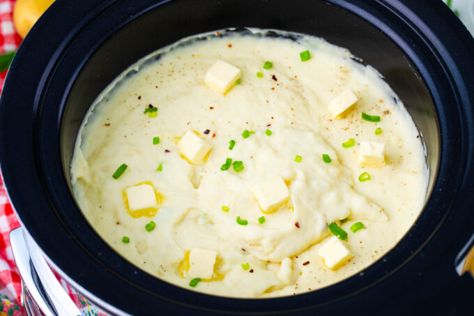 Homemade slow cooker mashed potatoes topped with butter and chopped green onions.
