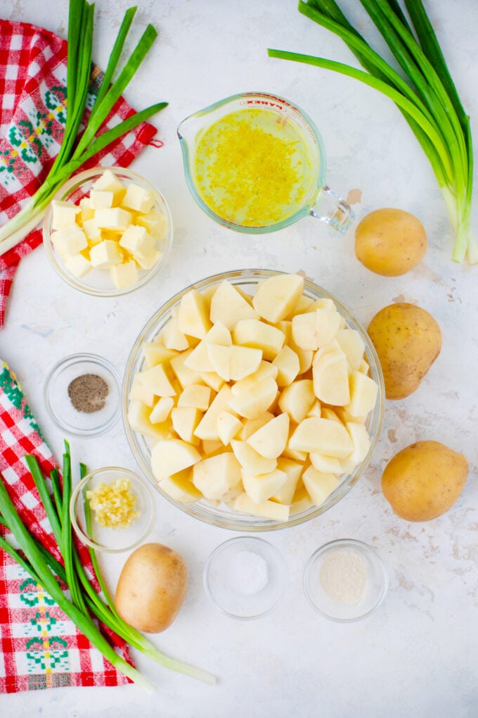 Overhead shot of slow cooker mashed potatoes ingredients in bowls on a table.