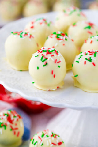 Sugar cookie truffles topped with sprinkles on a cake stand.