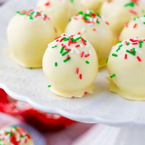 Sugar cookie truffles topped with sprinkles on a cake stand.