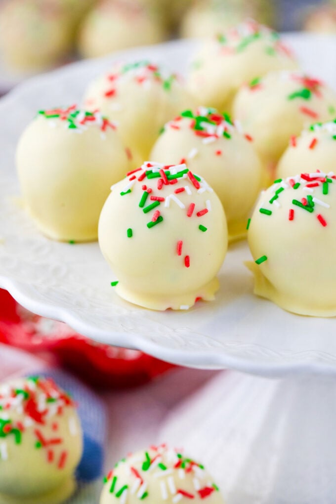 Sugar cookie truffles topped with sprinkles on a cake stand.