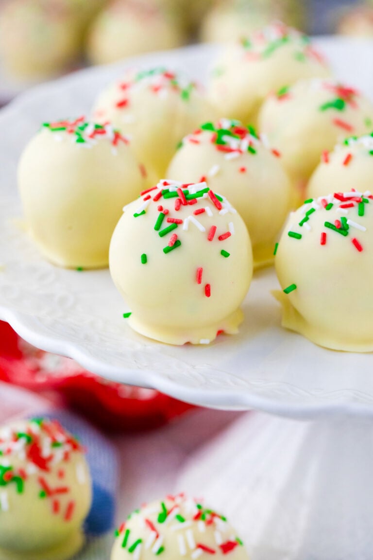 Sugar cookie truffles topped with sprinkles on a cake stand.