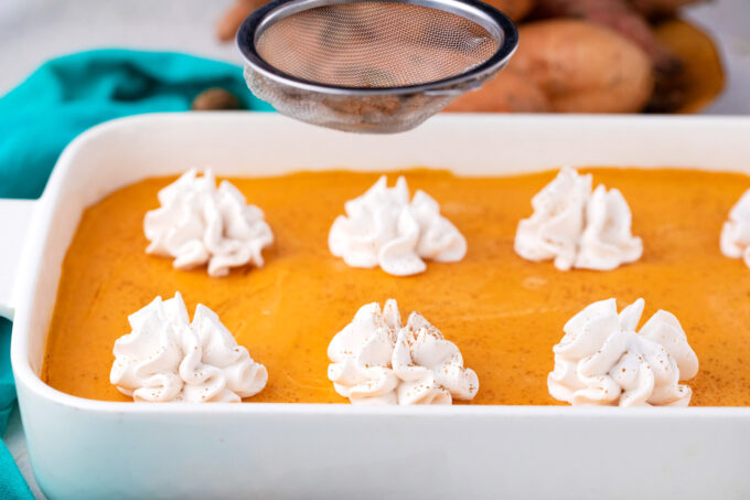 Sprinkling cinnamon on sweet potato cheesecake bars.