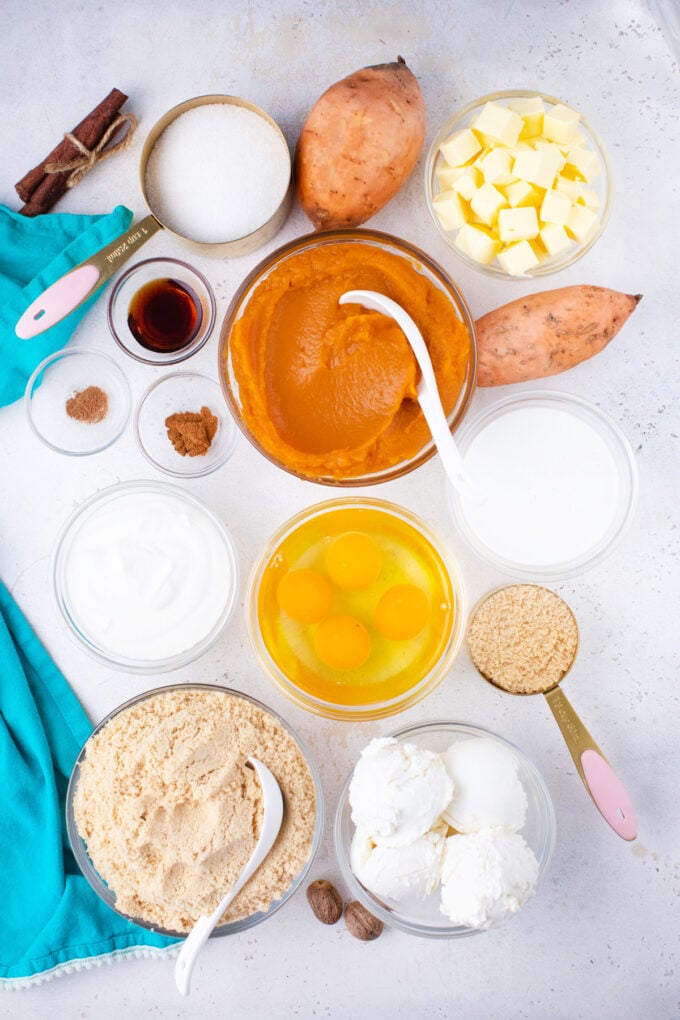Overhead shot of sweet potato cheesecake bars ingredients in bowls on a white surface.