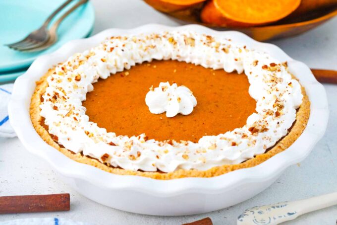 a whole sweet potato pie in a baking pie dish garnished with whipped cream