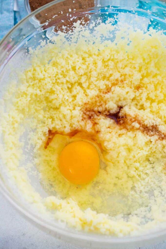 adding egg and vanilla to butter mixture in a bowl