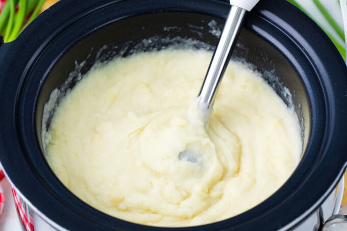 Whisking slow cooker mashed potatoes with a mixer.