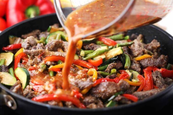 Adding Hunan sauce to beef and veggie stir-fry.