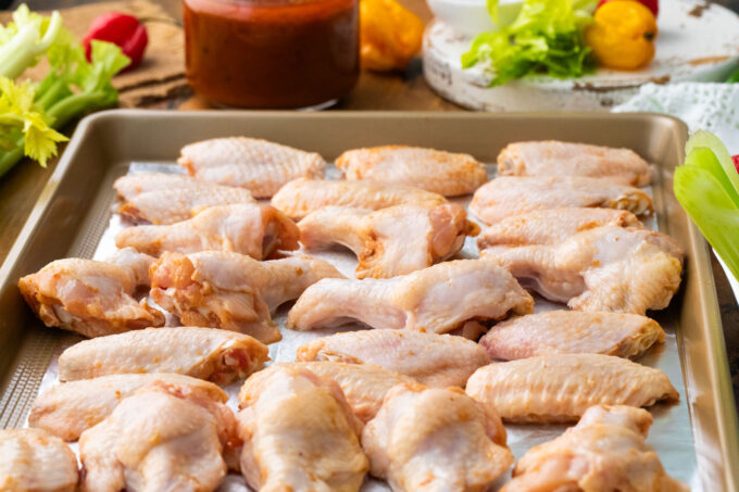 Raw buffalo wings on a wire rack.