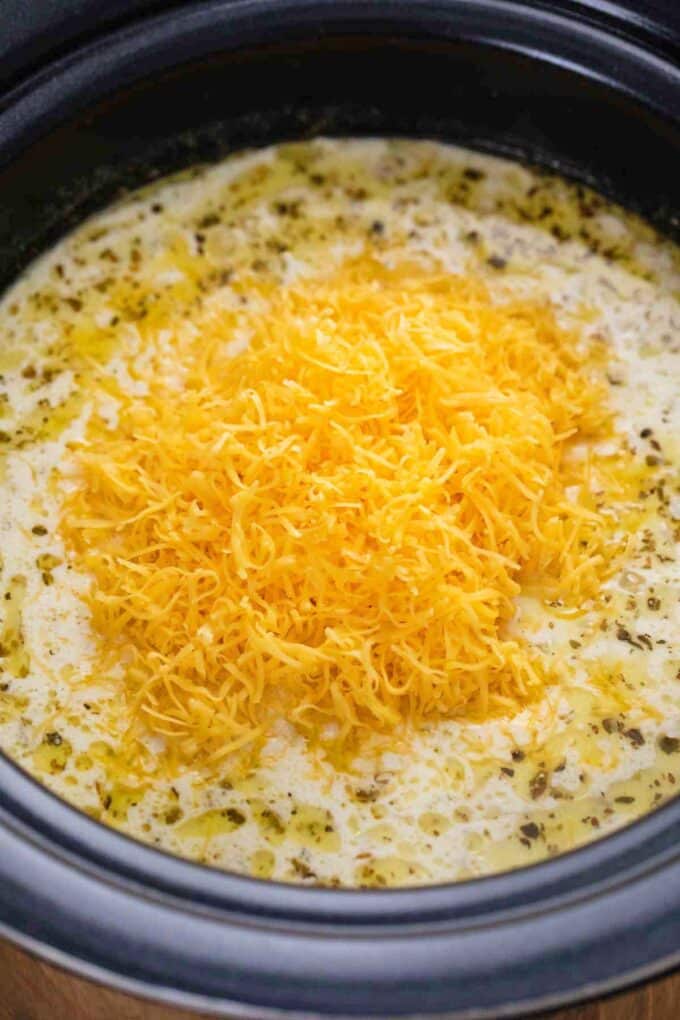 adding shredded cheddar cheese to creamy potato soup