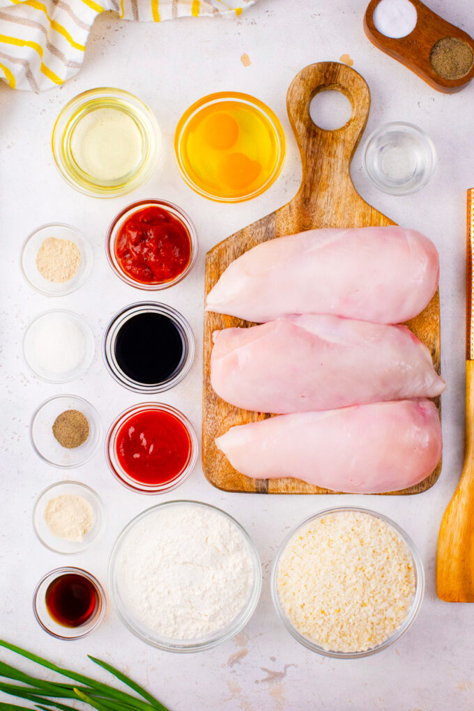 Overhead shot of chicken katsu with tonkatsu sauce ingredients arranged on a white table.