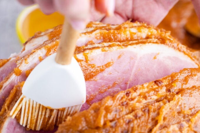 Coating spiral ham with honey butter sauce.