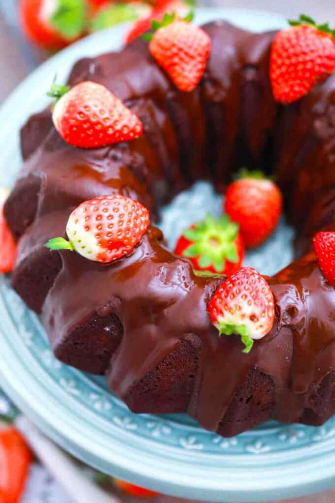 overhead shot of chocolate bundt cake topped with ganache and strawberries