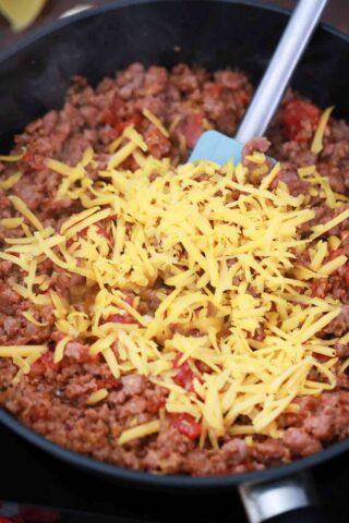 ground beef with cheddar cheese in a cast iron skillet