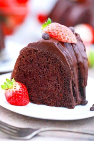 a slice of chocolate pound cake topped with chocolate ganache and fresh strawberries