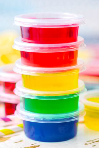 A stack of rainbow jello shots in a variety of colors.