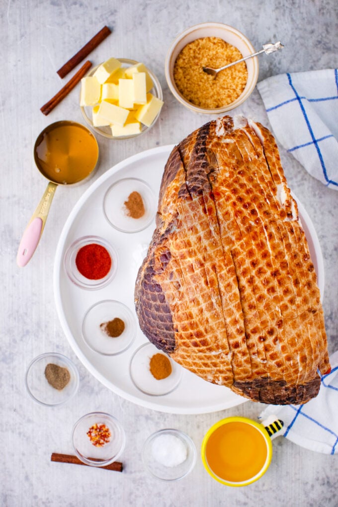 Overhead shot of oven baked honey butter ham ingredients arranged on a white surface.