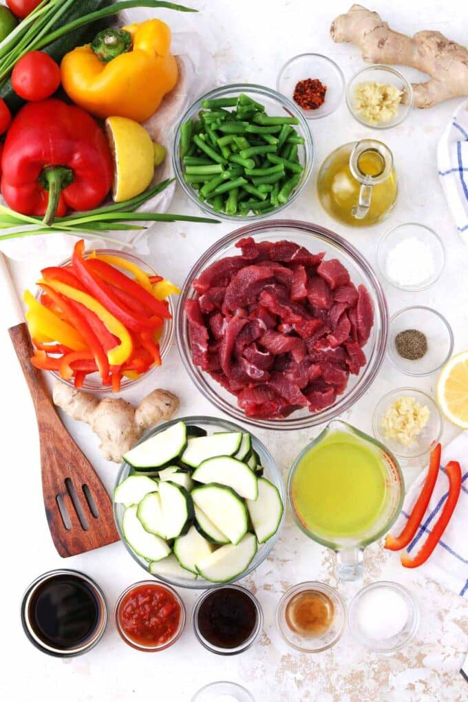 Hunan beef ingredients in bowls on a white surface.