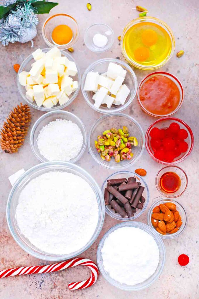 overhead shot of butter sugar chocolate jam nuts eggs and cherries in bowls on a table