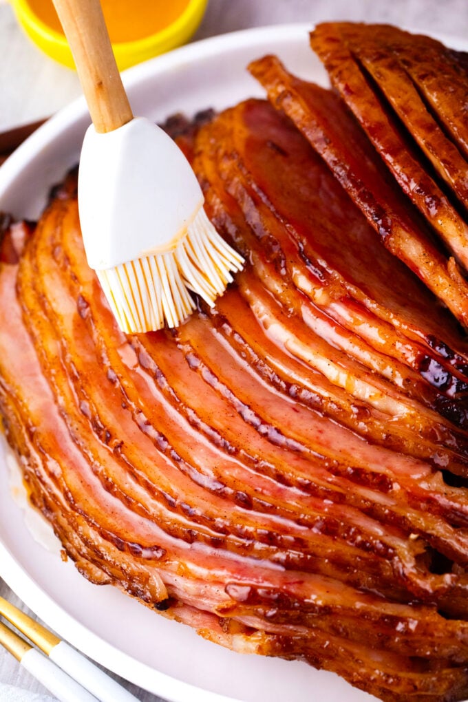 Brushing oven baked honey butter ham with sauce.