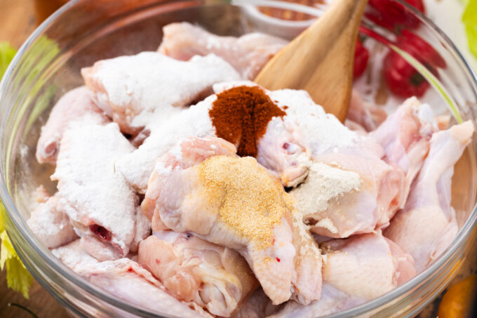 Mixing chicken wings and seasonings in a bowl.
