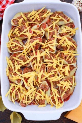 stuffed shells topped with cheddar cheese in a baking dish