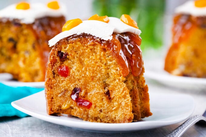 A slice of Simnel cake topped with apricot jam, marzipan, and dried apricots.